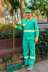 A dark-haired street sweeper standing in a park