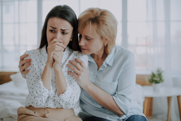 Confident worried mature mother embracing and helping sad daughter with broken heart, family support, mid aged mom soothe crying adult child, divorce or miscarriage, share problem with someone close - 781407887