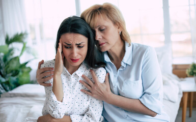 Confident worried mature mother embracing and helping sad daughter with broken heart, family support, mid aged mom soothe crying adult child, divorce or miscarriage, share problem with someone close - 781407899