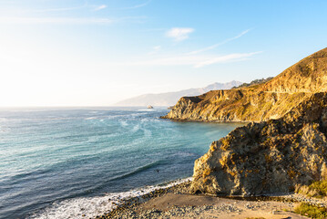 View of the hauntingly beautiful rugged coast of central California warmly lit by a setting sun in autumn