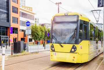 Yellow tram running along a street in a residential district - obrazy, fototapety, plakaty