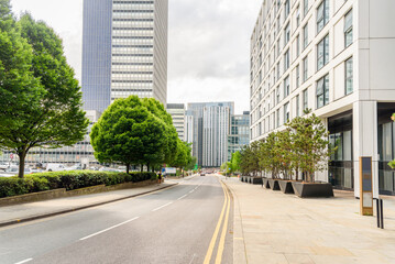 Street lined with modern office buildings and parking lots in a city centre on a cloudy summer day