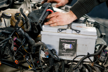 close-up At a service station the hands of a repairman remove the battery and replace it with a new one