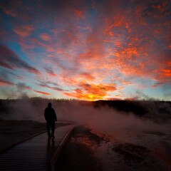 Sunrise near Yellowstone geysers with steam and silhouette of person on walkway - 781415417