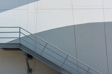 Steel stairs walking up and down, side of factory, building, wall with curved pattern of paint,...