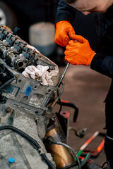 close-up At a service station young master repairs a motor part removed from a car for a complete...