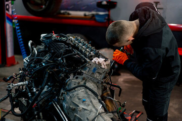 At a service station young master repairs a motor part removed from a car for a complete overhaul