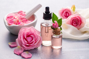 Bottles of essential rose oil and flowers