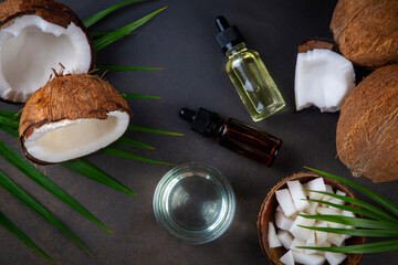 Bottle of coconut oil and fresh coconuts with palm leaf