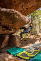 Boulder climber climbing with great technique and effort a stone roof in the Rodeno pine forest in...