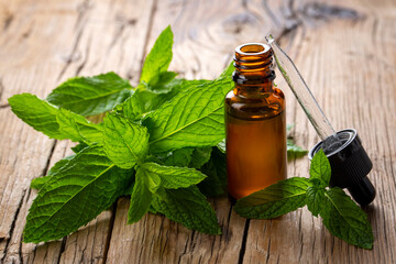 Bottle of mint essential oil and mint green leaves