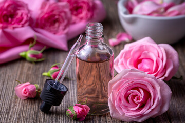 Bottles of essential rose oil and flowers