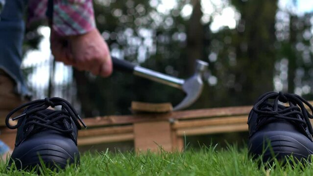 Work boots with recycling wooden industrial pallet with a hammer background
