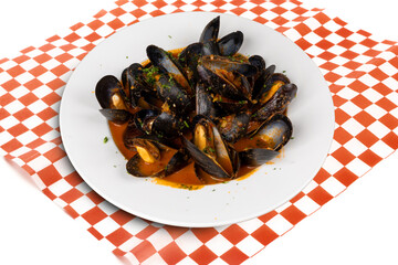 A white plate of steamed mussels in wine sauce on a red checked table