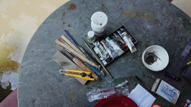 Paints and paintbrushes on a table.  Ubud, Bali, Indonesia.