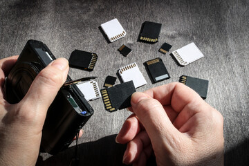 Close-up of hands inserting a memory card into the camera's memory slot, with SD and MicroSD flash cards in the background