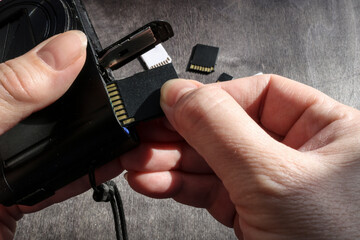 Close-up of hands inserting a flash card into the camera's memory slot. - 781434630