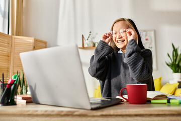 A young Asian girl, engrossed in e-learning, sits in front of a laptop computer at home.