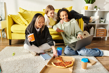 Three teenage girls of different ethnicities sit comfortably on the floor, enjoying slices of pizza...