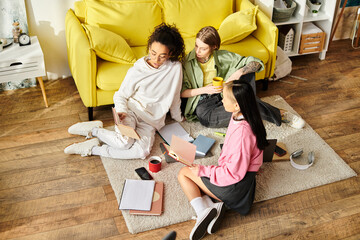 A group of interracial teenage girls sitting on the floor, studying together next to a bright...