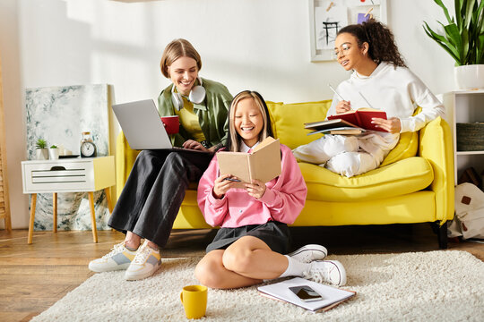 A diverse group of teenage girls sit closely together on a vibrant yellow couch, engrossed in studying and deep in conversation. - Powered by Adobe