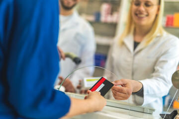 Customer using credit card to pay the bill for medications in a drugstore, pharmacy. - obrazy, fototapety, plakaty