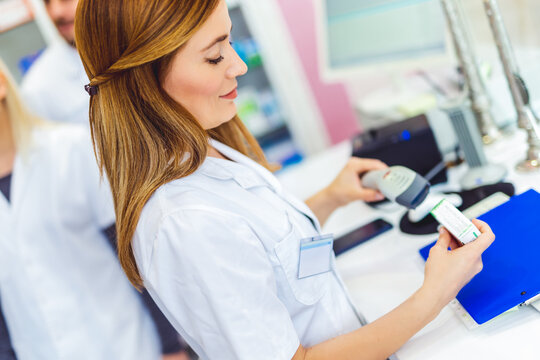 Pharmacist scanning price on a medicine box with barcode reader in pharmacy store.