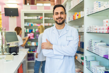 Smiling portrait of young handsome male pharmacist at the pharmacy, drugstore.
