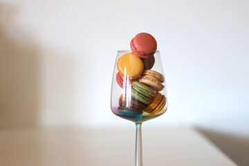 Champagne glass full of colorful macaroons on the table. Selective focus.