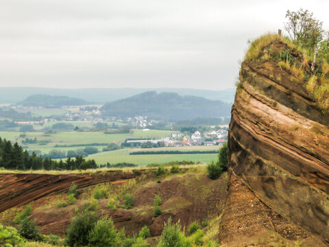View over an abandoned Tephra quarry with a hazy view of villages in the Brohl Valley, in the western part of Vulcaneeifel Geopark in Germany.