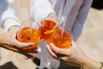 Two hands with glasses of Aperol spritz cocktail