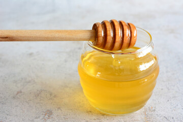 honey in a jar with a wooden dipper isolated close up