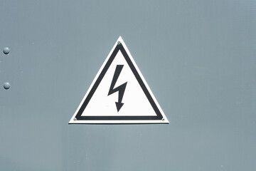 Sign on a gray metal surface, means caution, live object