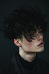 Moody close-up photo capturing a young man's messy fringe hairstyle against a dark background