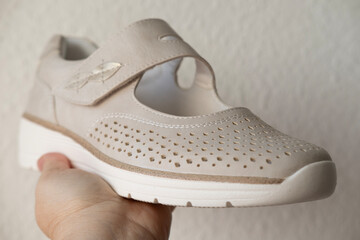 new beige leather shoe, comfortable perforated moccasin in female hands, buying new women's shoes,...