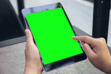 Mockup image of hands holding and touching a black tablet pc with blank desktop screen on table