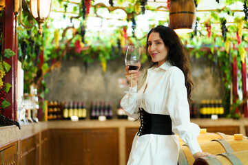 Portrait of beautiful caucasian young woman enjoy testing the red wine and showing a wine glass to camera. Woman testing a wine.