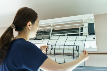 Woman cleaning air conditioner filter which is full of dust.