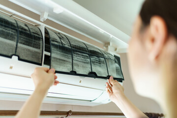 Woman cleaning air conditioner filter which is full of dust.