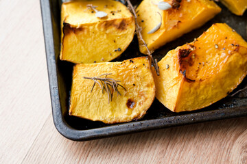 Pieces of organic oven roasted butternut squash in a baking sheet pan with fresh thyme and sage...