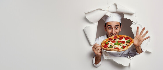 A surprised chef pops out through a paper hole, holding a pepperoni pizza with excitement