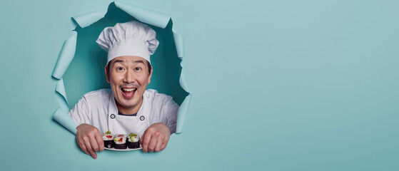 A jubilant chef holding sushi through torn teal paper, symbolizing passion and creativity