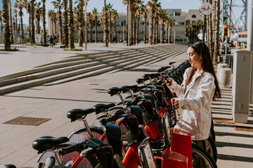 Obraz premium A serene spring afternoon in Barcelona with a smiling woman renting a bicycle