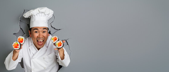 An excited Asian chef in a classic chef's uniform displays a sushi selection while breaking through a tear in a light background