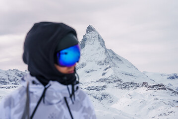 Person in white jacket, ski goggles, near Matterhorn mountain in Zermatt, Switzerland. Winter sports, alpine views, luxury accommodations in scenic photo.