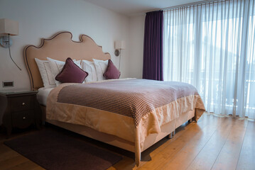 Luxurious hotel room in Zermatt, Switzerland. Large bed with elegant headboard, white linens,...