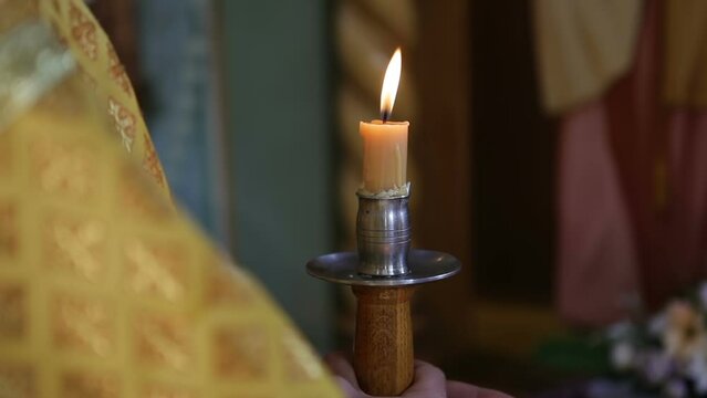 The deacon holds a burning wax candle in his hands. Church services for Christians.