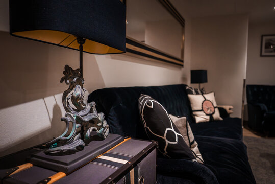 Luxurious hotel lounge in Zermatt, Switzerland. Focus on ornate dragon lamp casting warm glow on blue velvet sofa with decorative pillows. Opulent, sophisticated decor for exclusive alpine ambiance.