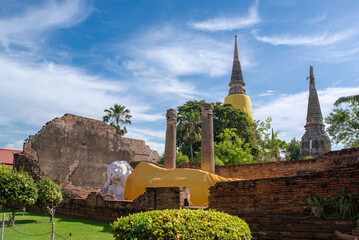 Historic site in Thailand featuring a reclining Buddha statue, ancient stupas, and weathered brick...