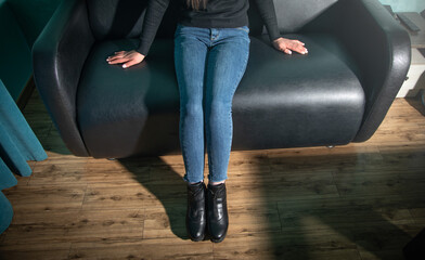 Woman sitting on black leather couch at home.